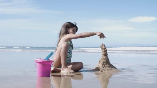 Happy cute little girl budynku zamek z piasku na plaży — Wideo stockowe