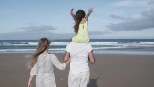 Para rodziców z małą córeczką spacerującą po plaży — Wideo stockowe