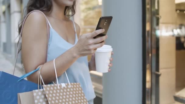 Vista recortada de la mujer con café escribiendo en el teléfono inteligente — Vídeos de Stock
