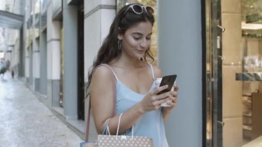 Gülümseyen kadın akıllı telefon kullanıyor, sohbet okuyor ve kahve içiyor.
