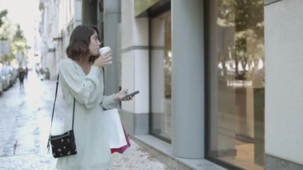 Латинская женщина ходит по улице, пьет кофе и смотрит — стоковое видео
