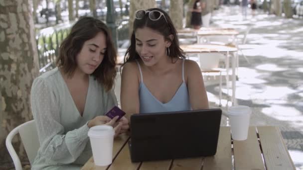 Jovens amigas sentadas no café da cidade e usando laptop — Vídeo de Stock