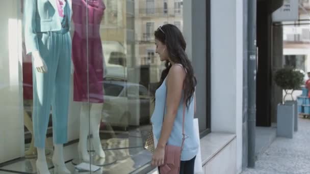 Gyönyörű hölgy hívja barátja és bemutató ruhák a kirakatban — Stock videók