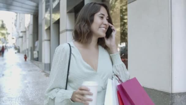 Senhora latina andando perto de lojas, falando no smartphone — Vídeo de Stock