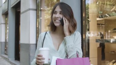 Neşeli Latin kadın cep telefonuyla konuşuyor ve gülümsüyor.