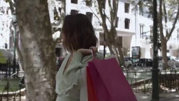 Молодая красивая женщина держит мешки на плече и ходить — стоковое видео