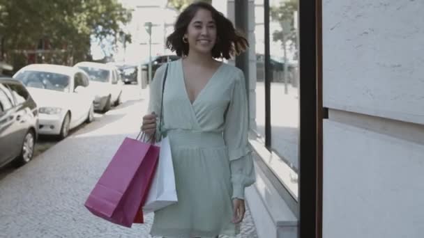 Mulher feliz andando ao longo da rua com sacos de compras — Vídeo de Stock