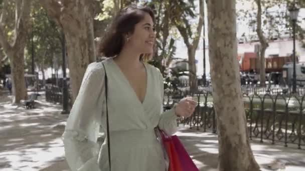 Wanita muda Latin memegang tas di siku dan berjalan di jalan — Stok Video