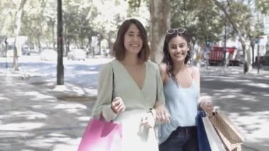 İki güzel kadın sokakta alışveriş çantalarıyla yürüyor.