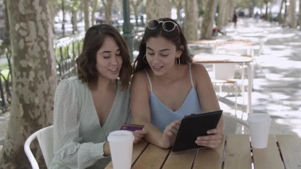 快乐的女性朋友坐在城市咖啡馆里用平板电脑 — 图库视频影像