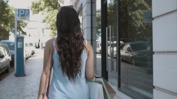 Langharige vrouw die langs straat loopt met boodschappentassen — Stockvideo