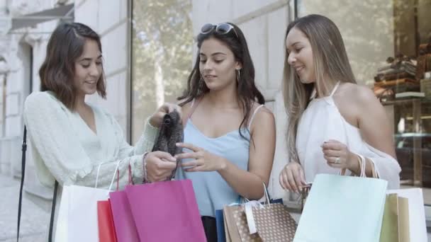 Szczęśliwe młode kobiety stojące na ulicy i przymierzające ubrania — Wideo stockowe