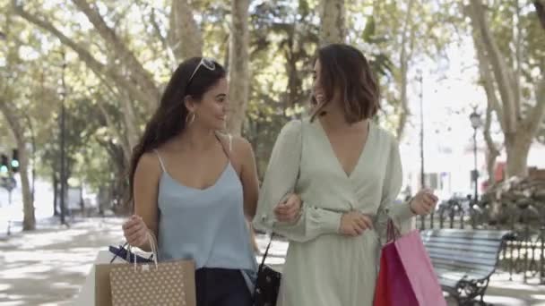 Vue de face de deux femmes marchant avec des sacs à provisions le long de la rue — Video