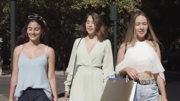 Jeune femme marchant le long de la rue avec des sacs à provisions, souriant — Video