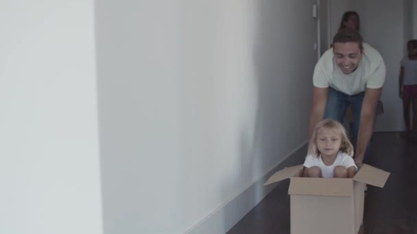 Gelukkig vader slepen doos met kleine dochter binnen — Stockvideo