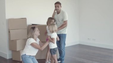 Neşeli ebeveynler ve iki kız yeni evlerinde dans ediyorlar.