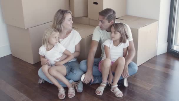 Ευτυχισμένο οικογενειακό ζευγάρι και δύο κόρες κάθονται στο πάτωμα — Αρχείο Βίντεο