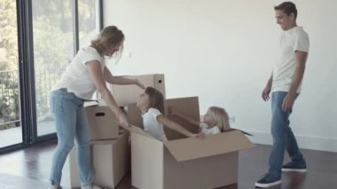 Ebeveynler içinde neşeli kızlar olan büyük bir çizgi film kutusu açıyor.