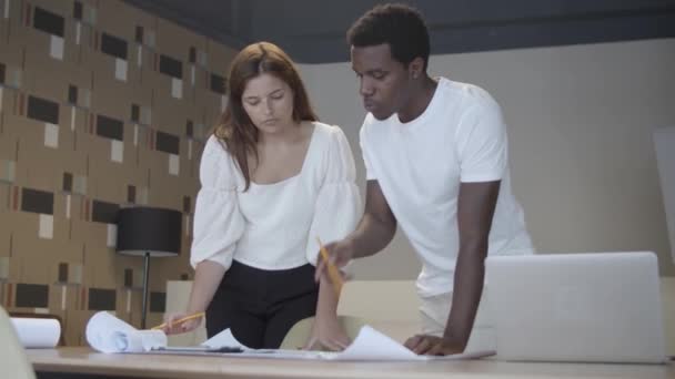 Diverse collega 's ontmoeten elkaar aan tafel met blauwdruk — Stockvideo