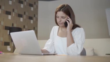 Genç bayan girişimci cep telefonuyla konuşuyor.