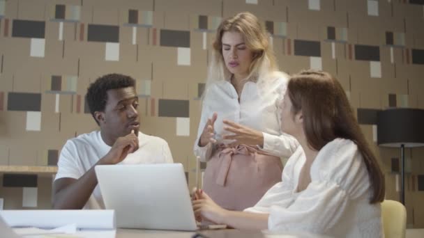 Креативная команда сидит и стоит за столом с ноутбуком — стоковое видео