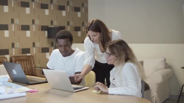 Skupina různých spolupracovníků sedí a stojí u stolu — Stock video