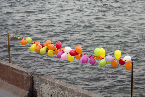 Soft baloons in a row and concrete barriers with gray sea background: Soft and hard borders for migrants concept.