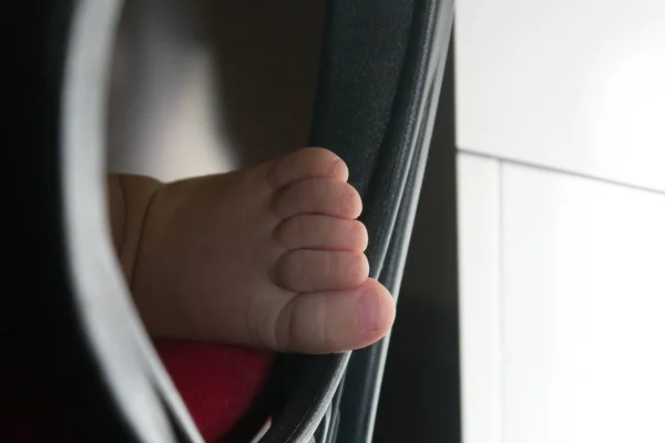 A toddler\'s little foot framed by parent\'s office chair\'s handle, in front of a white desk