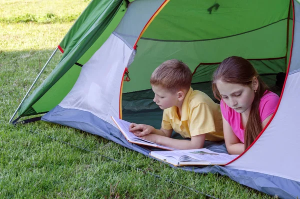 Girl and boy read a book in the tent
