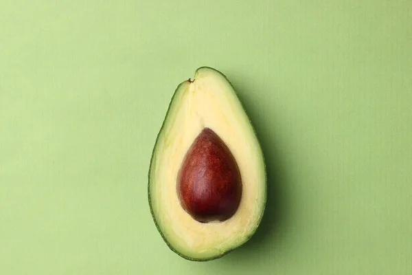 Halbe Avocado mit Samen auf grünem Hintergrund von oben — Stockfoto