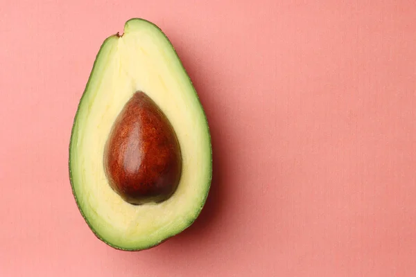 Avocado with seed on coral background. half avocado on green background — Stock Photo, Image