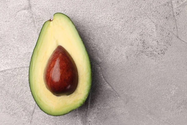 Half avocado with seed on cement background top view — Stock Photo, Image