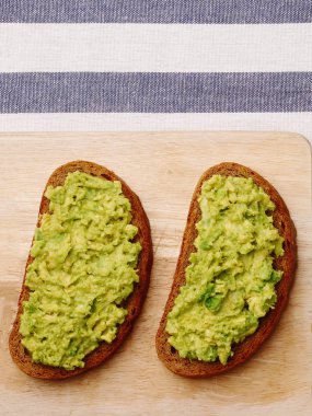 açık renkli guacamole sandviç. ahşap tahta ve Tekstil üstten görünüm üzerinde avokado sandviç
