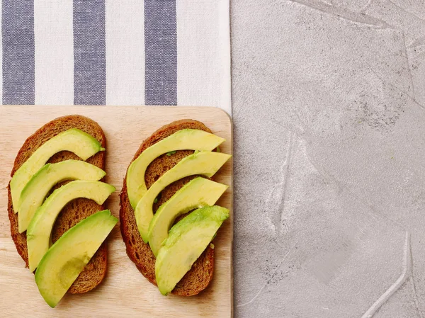 Avokado karanlık çavdar ekmeği üstten görünüm ışık Tekstil zemin üzerine dilimlenmiş. Kahvaltı konsepti