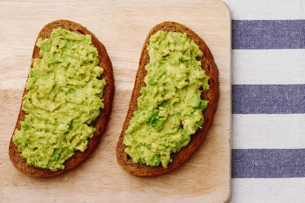 Sandwich con guacamole su sfondo tessile chiaro vista dall'alto. panini su tavola di legno — Foto Stock