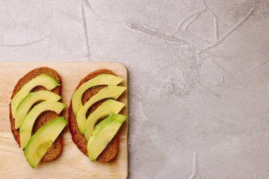Taze doğranmış avokado ile yapılan koyu siyah ekmek üzerinde avokado sandviç