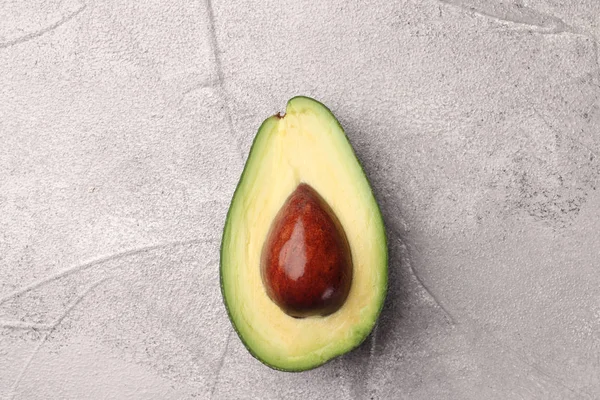 Half avocado with seed on cement background top view — Stock Photo, Image