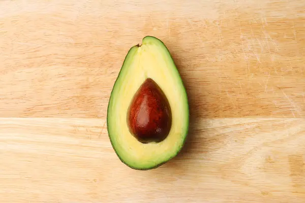 Half avocado on wooden background top view — Stock Photo, Image