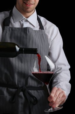 Barmen koyu arkaplanda bardağa şarap doldurur.