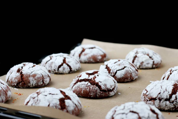 Chocolate cookies with cracks on baking paper and iolated on black. Cracked chocolate biscuits — Stock Photo, Image