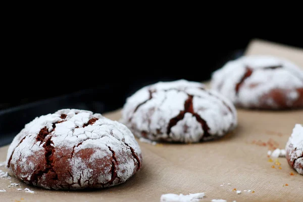 Chocolate cookies with cracks on baking paper and iolated on black. Cracked chocolate biscuits — Stock Photo, Image