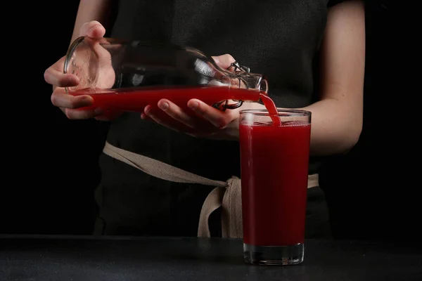 Chica vertiendo jugo en vidrio sobre fondo oscuro. concepto de bebida de verano — Foto de Stock