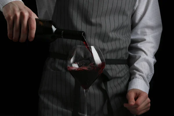 Bartender derrama vinho em vidro no fundo escuro — Fotografia de Stock