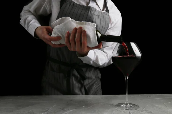 Bartender derrama vinho em vidro no fundo escuro — Fotografia de Stock