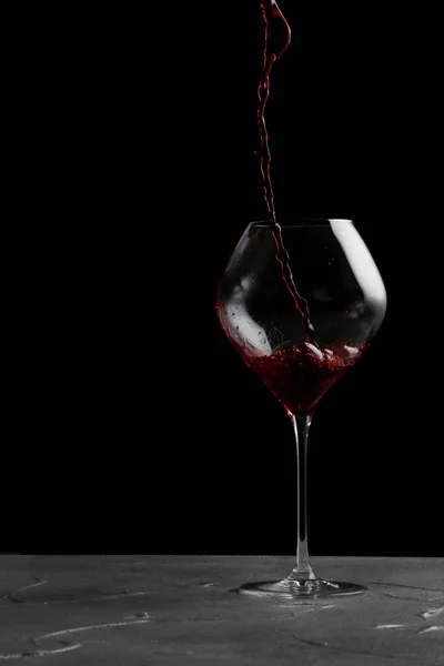 Vinho tinto derramando em vinho isolado em preto — Fotografia de Stock