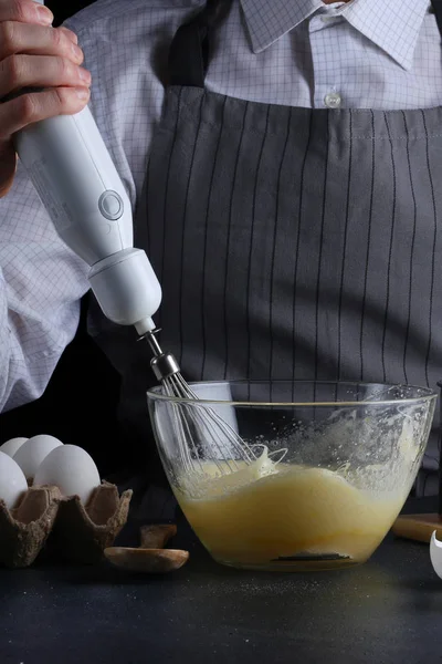 Şef yemek pasta ingridients tablo ile elinde karıştırıcılı