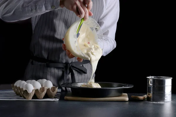 Hamur çırpıcıdan dökülüyor. Adam turta yiyor. Koyu arkaplanda tarif kavramı