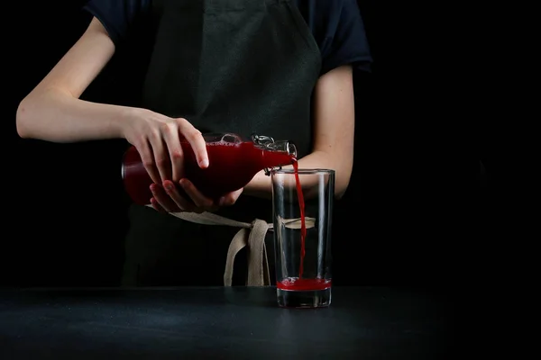 pouring juice in glass on dark background