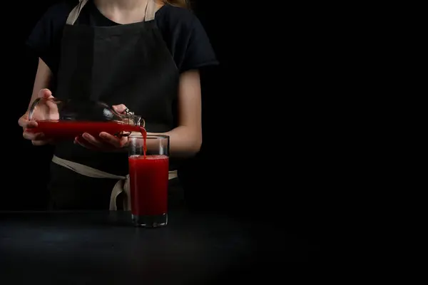 pouring juice in glass on dark background