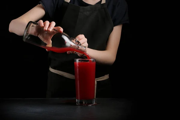 pouring juice in glass on dark background